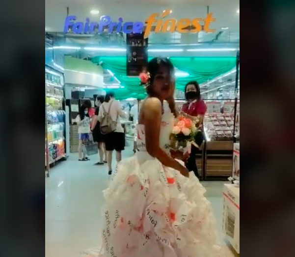 Woman wears dress made out of FairPrice plastic bags, performs fashion model walk at FairPrice Finest supermarket