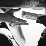 Hands passing money under table corruption bribery