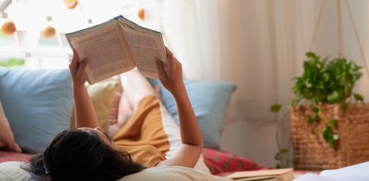 A woman reading a book in her bed.