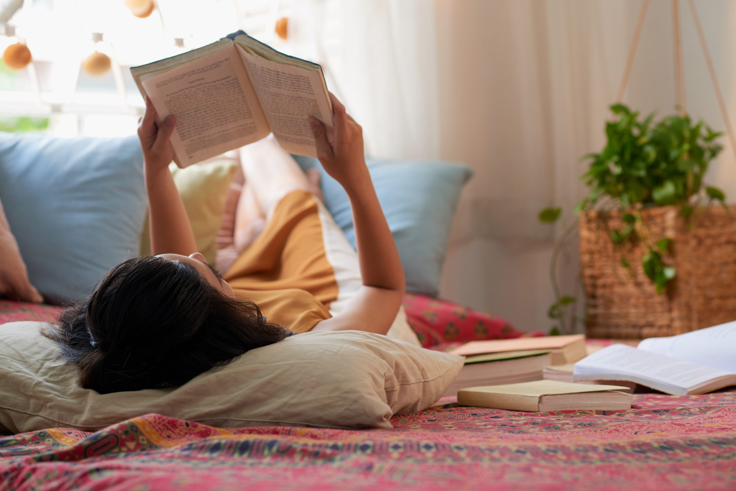 A woman reading a book in her bed.