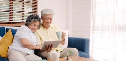 elderly asian couple looking at a tablet while having coffee