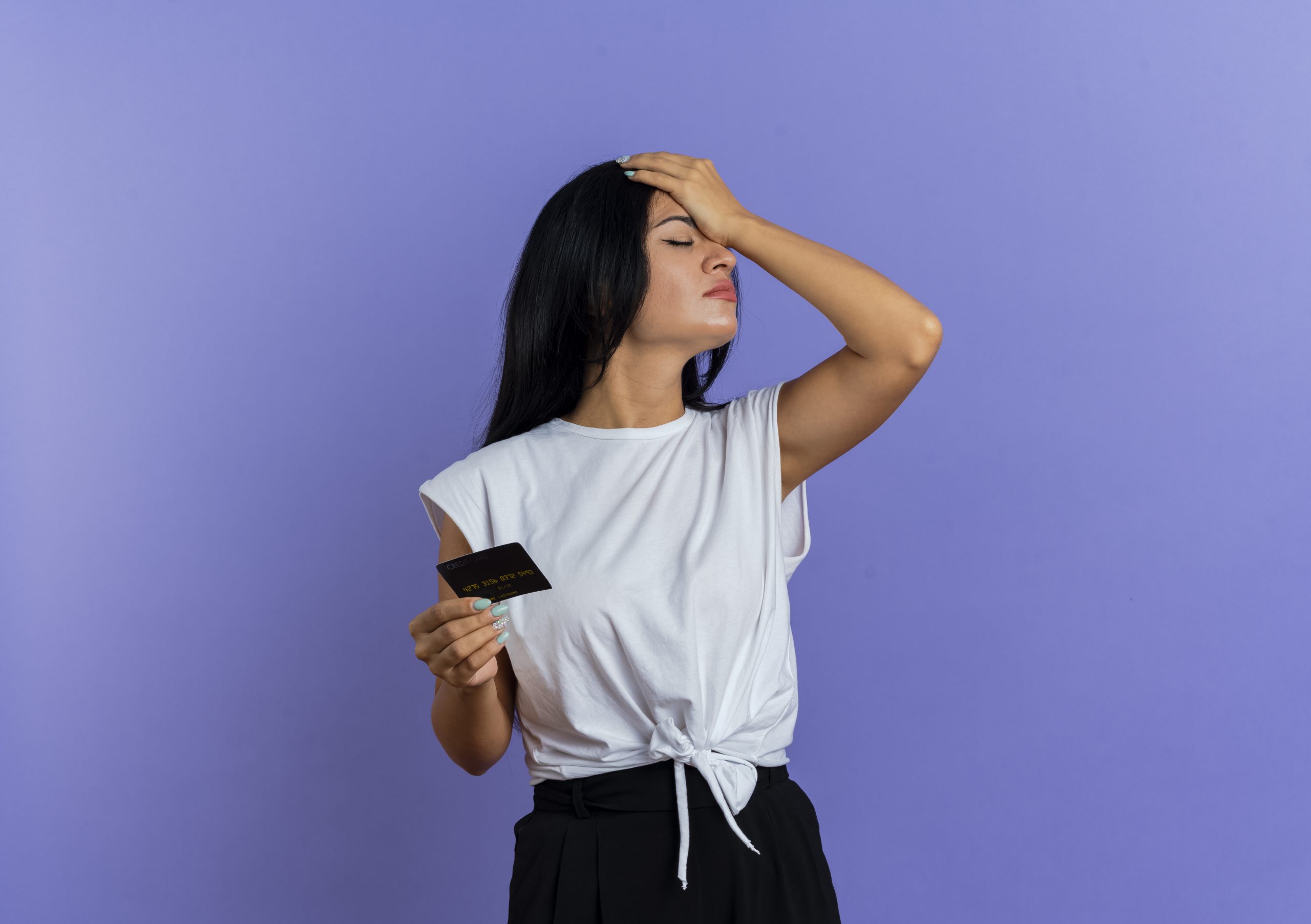 Woman holding a credit card while covering her face.