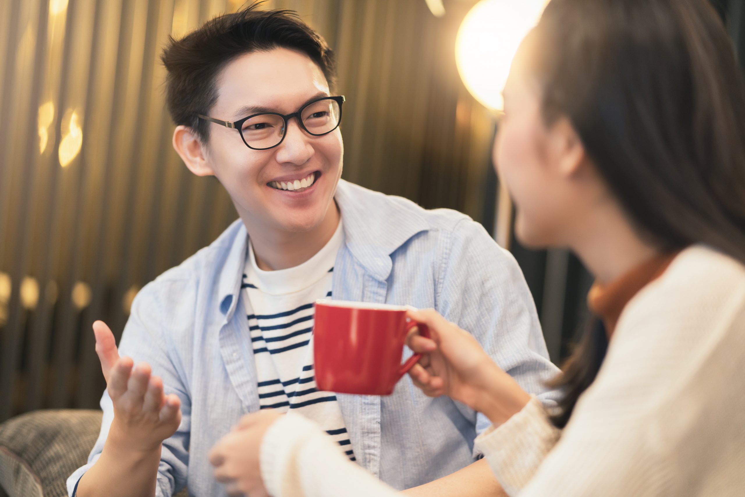 Happy man talking to a woman holding a red cup.