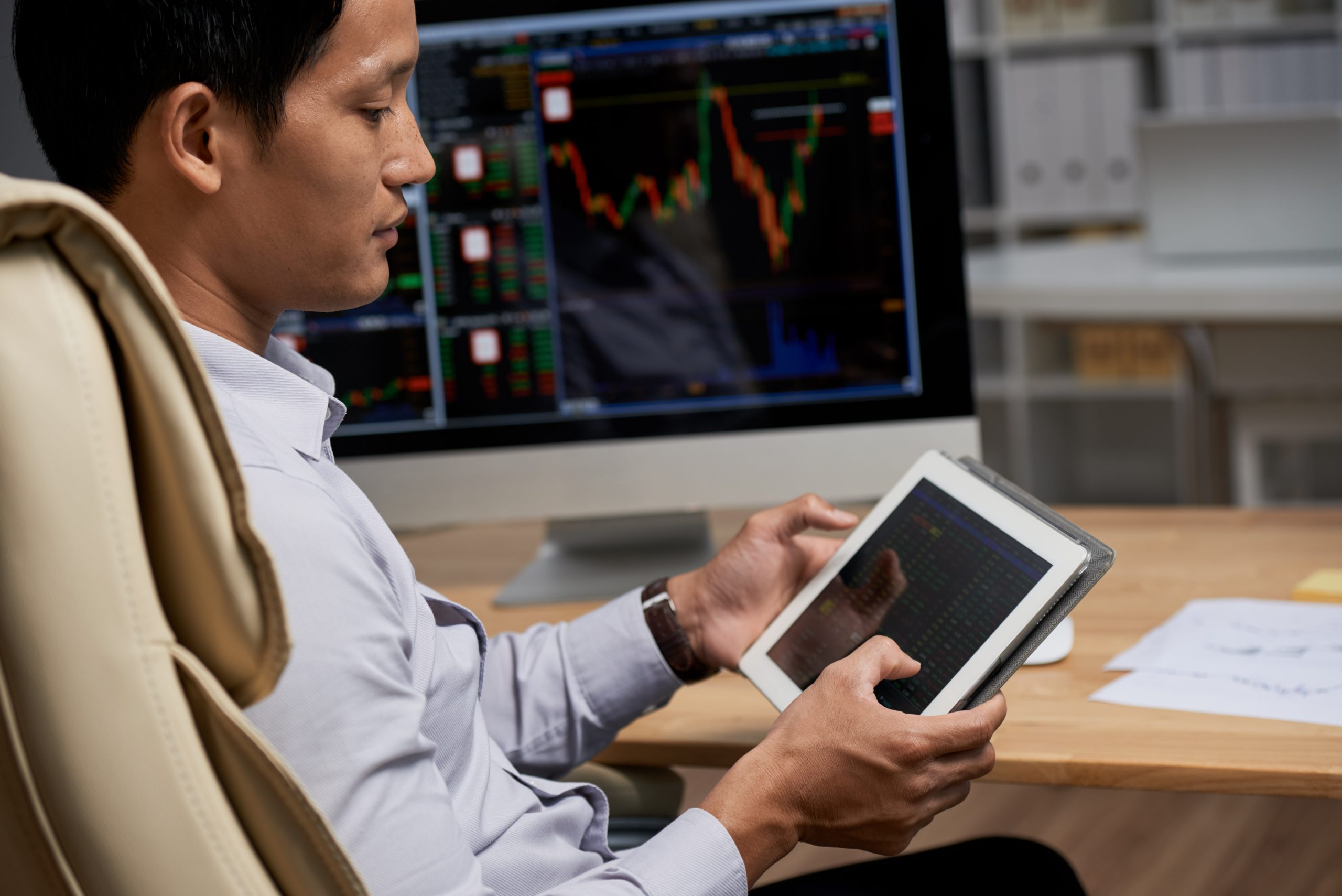 Man looking at tablet with stock market on the computer.