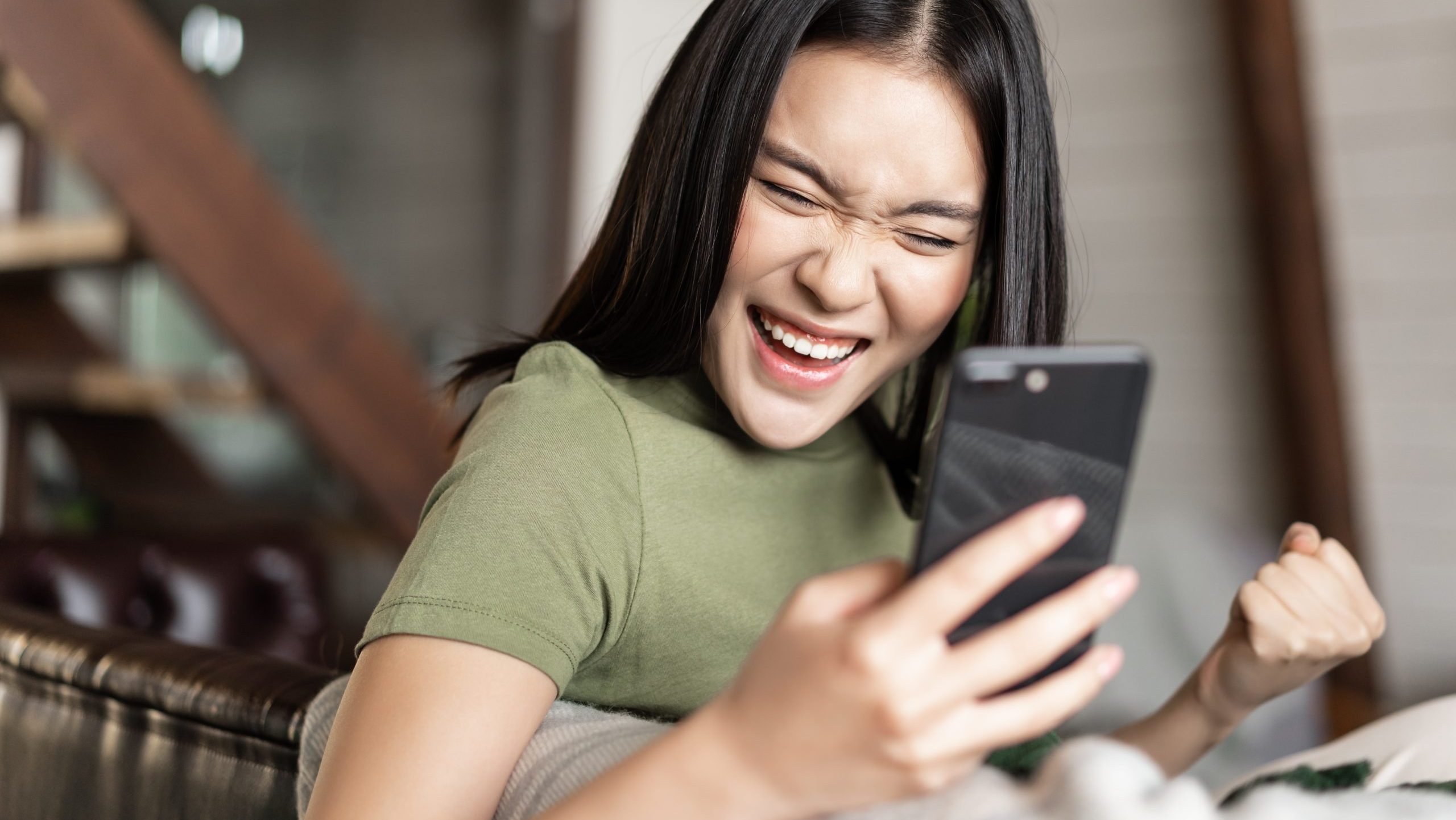 Smiling Asian woman looking at phone.