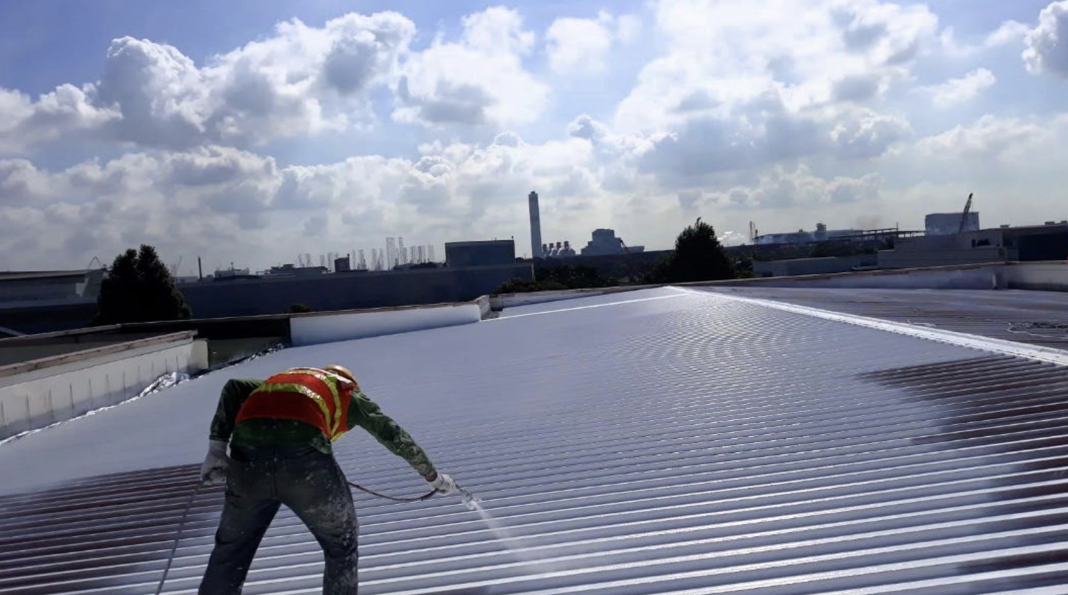 A worker spraying a coat of cool paint on the roof of a building at the test-site in Singapore.