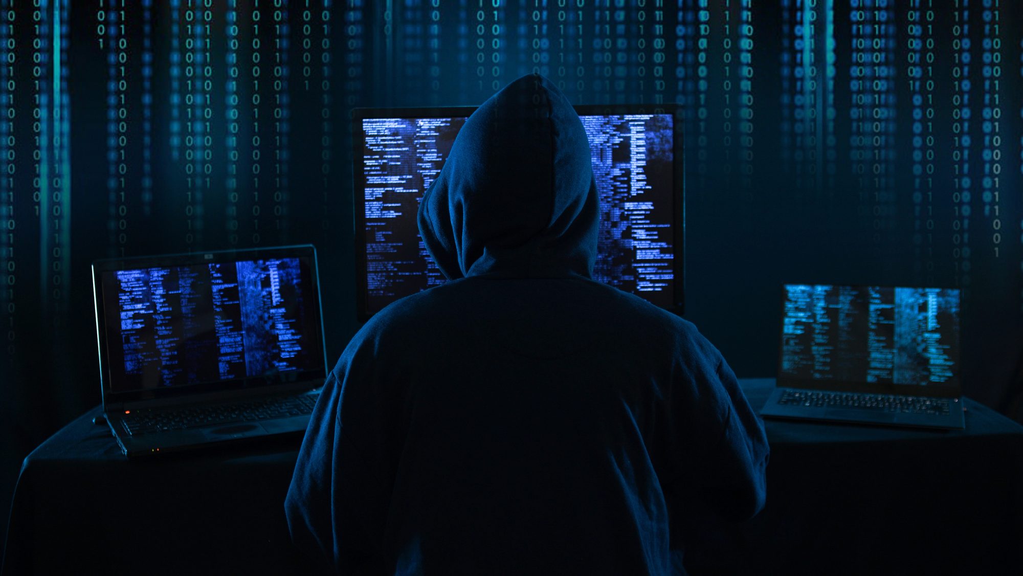Man with hoody hacking system