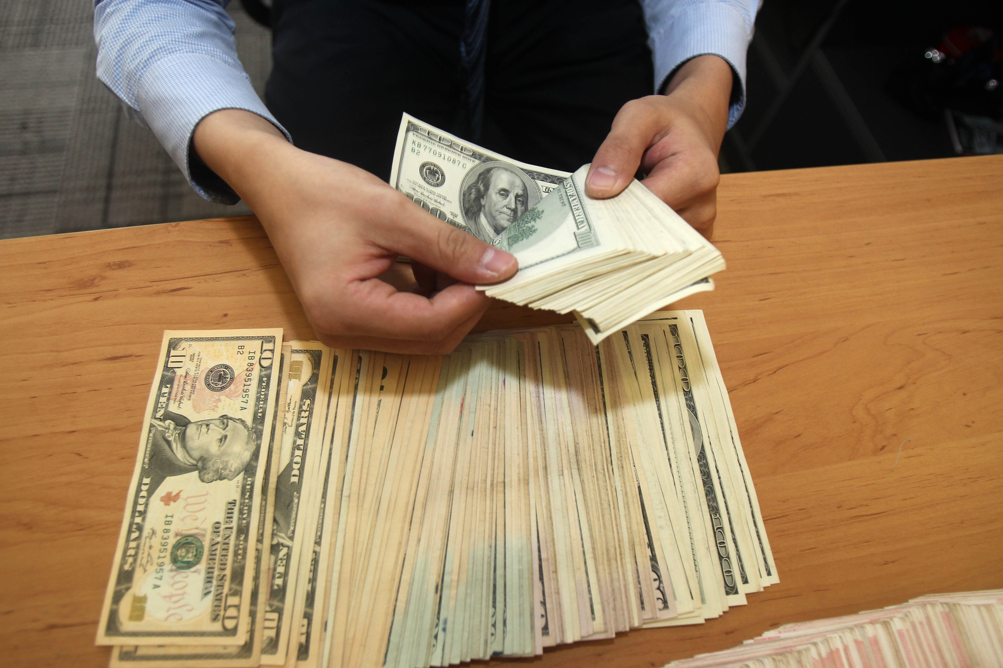 Man's hands counting money on table.