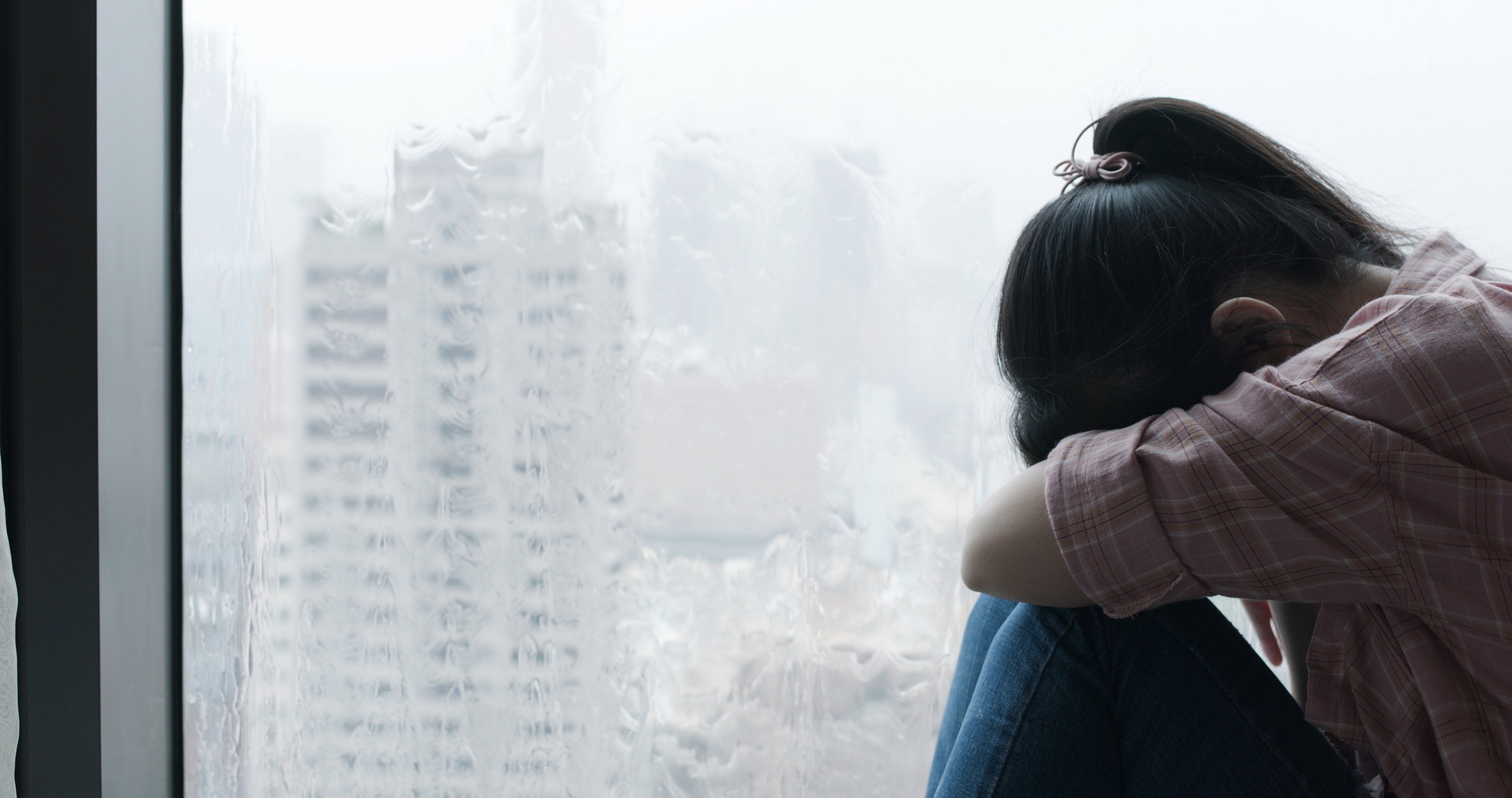 Depressed woman near a glass window.