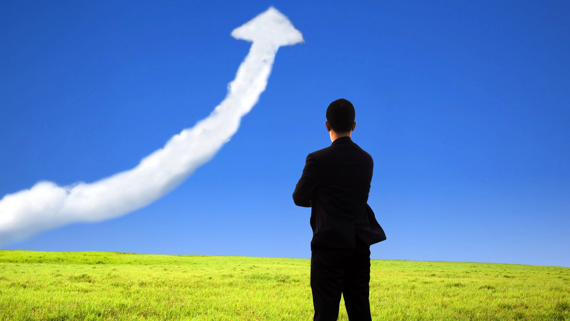 Businessman looking at an arrow going up in the sky.