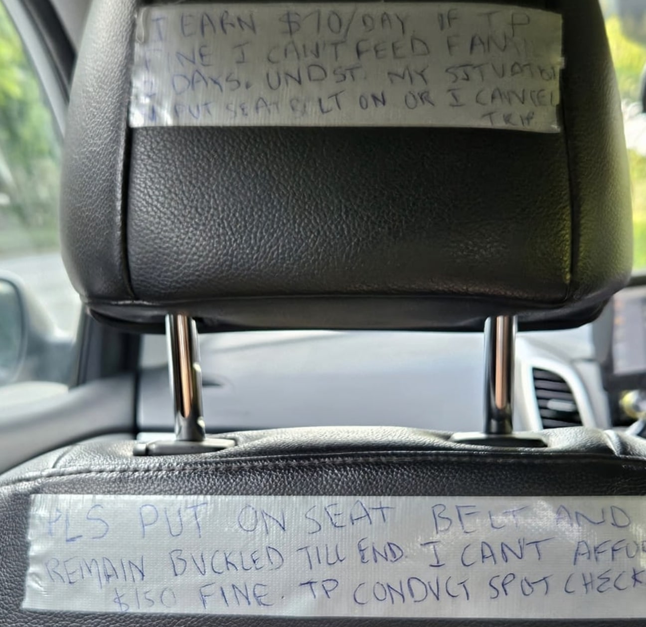 Taxi drivers backseat with handwritten note to passenger.