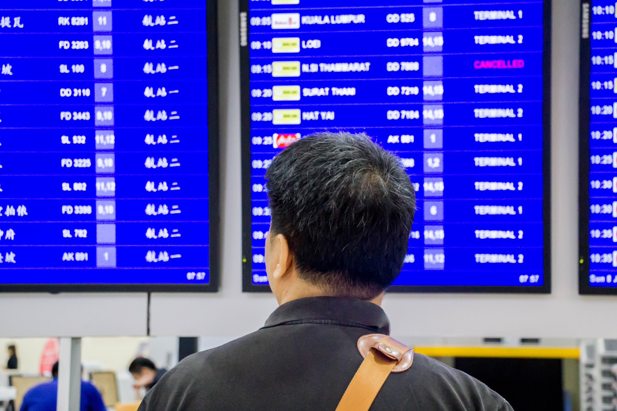 Asian man looking at the airport flight timetable