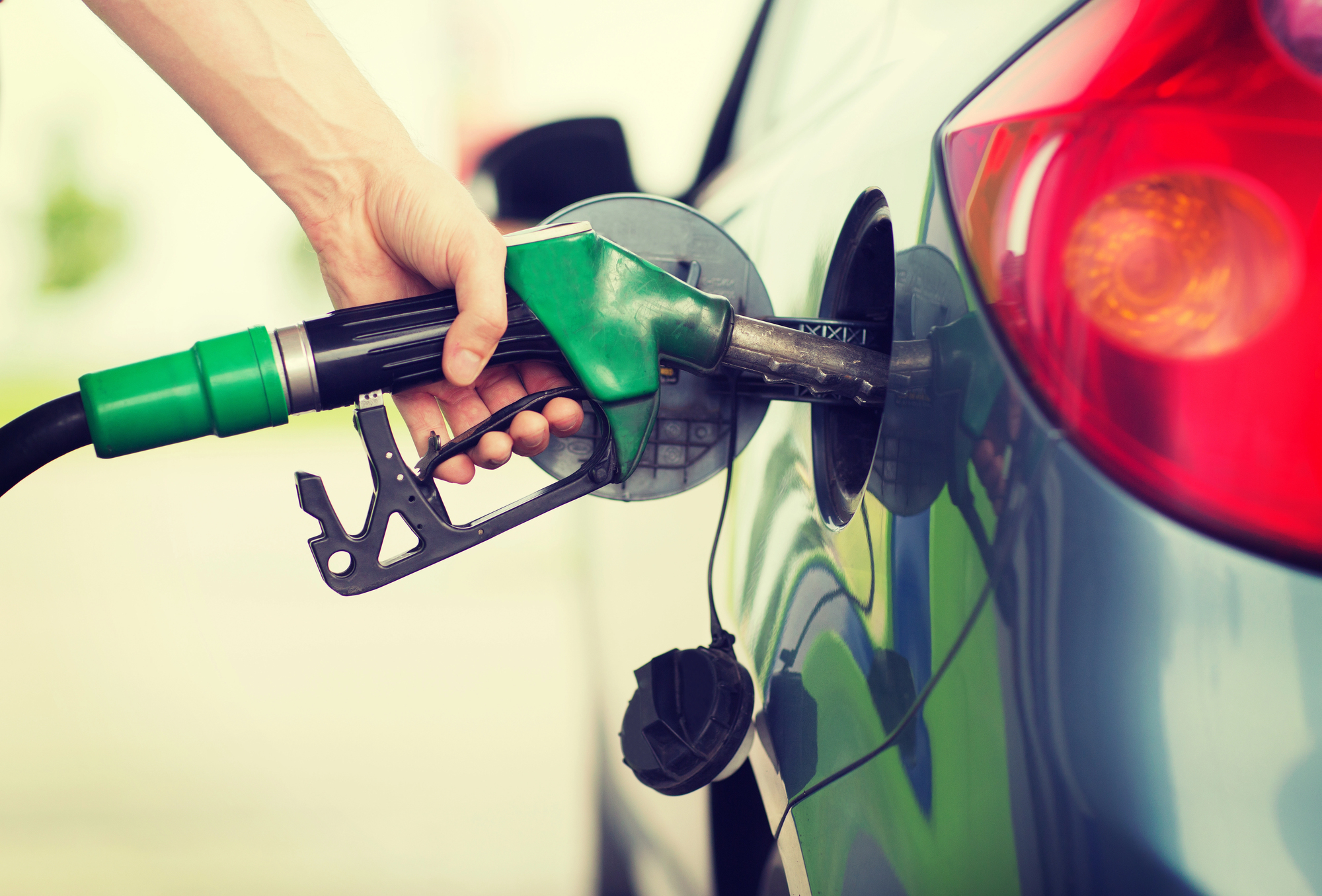 Hand pumping petrol in car at petrol station.