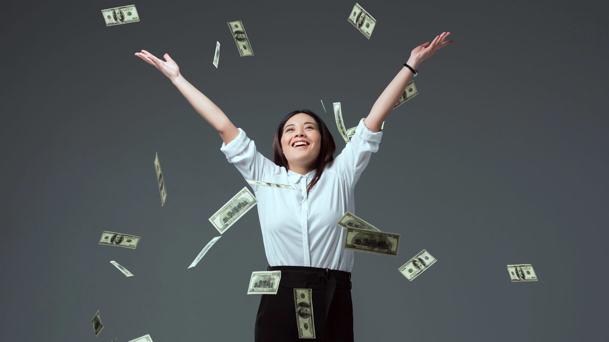 Happy young asian woman throwing money in the air.