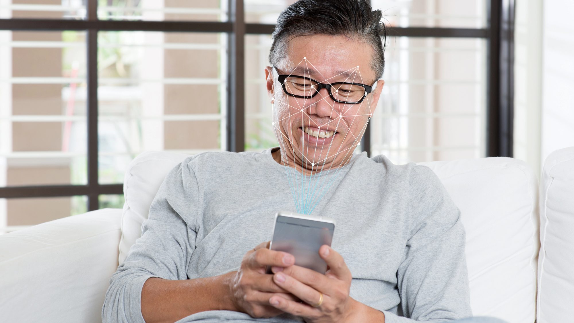 Asian man using phone for face recognition.