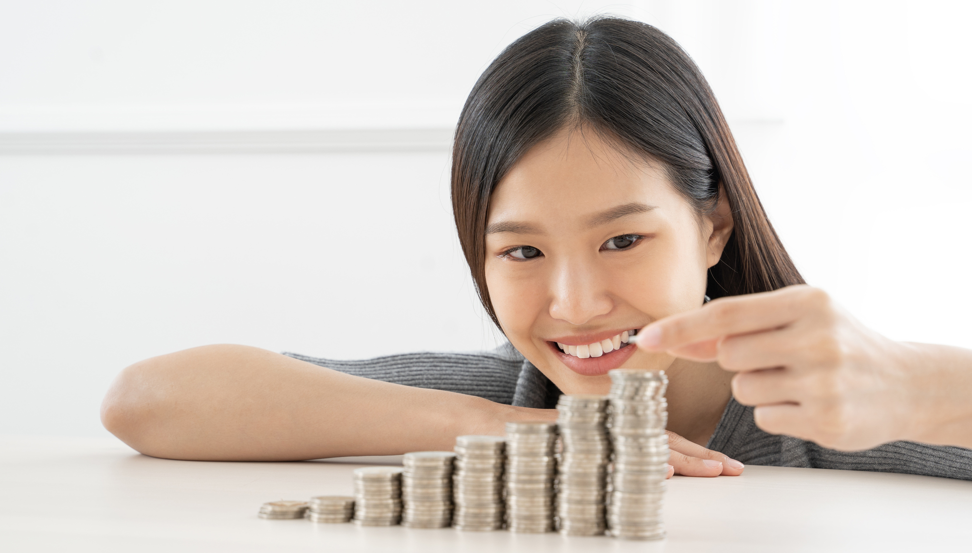 Young Asian woman making stack of coins.