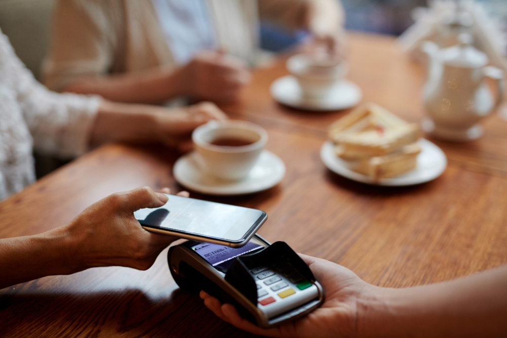 Man using his phone, through digital payment, to pay at a cafe.