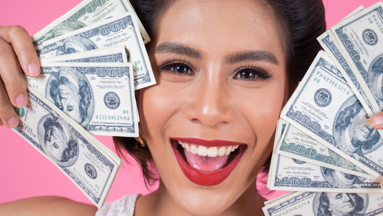 Woman holding a dollars on her face.