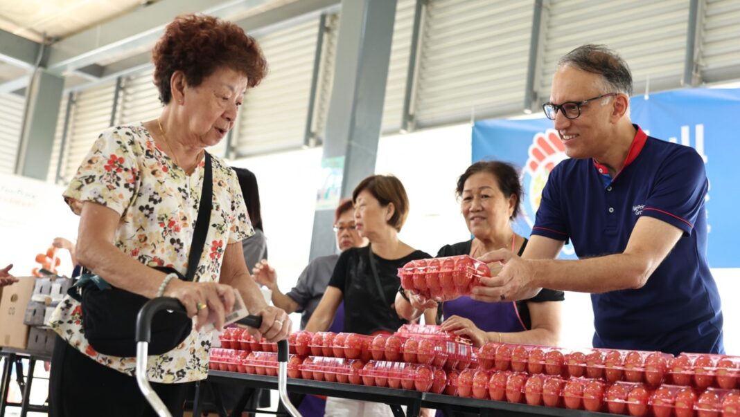 Senior receiving a tray of eggs as part of FairPrice Group's fresh protein initiative.