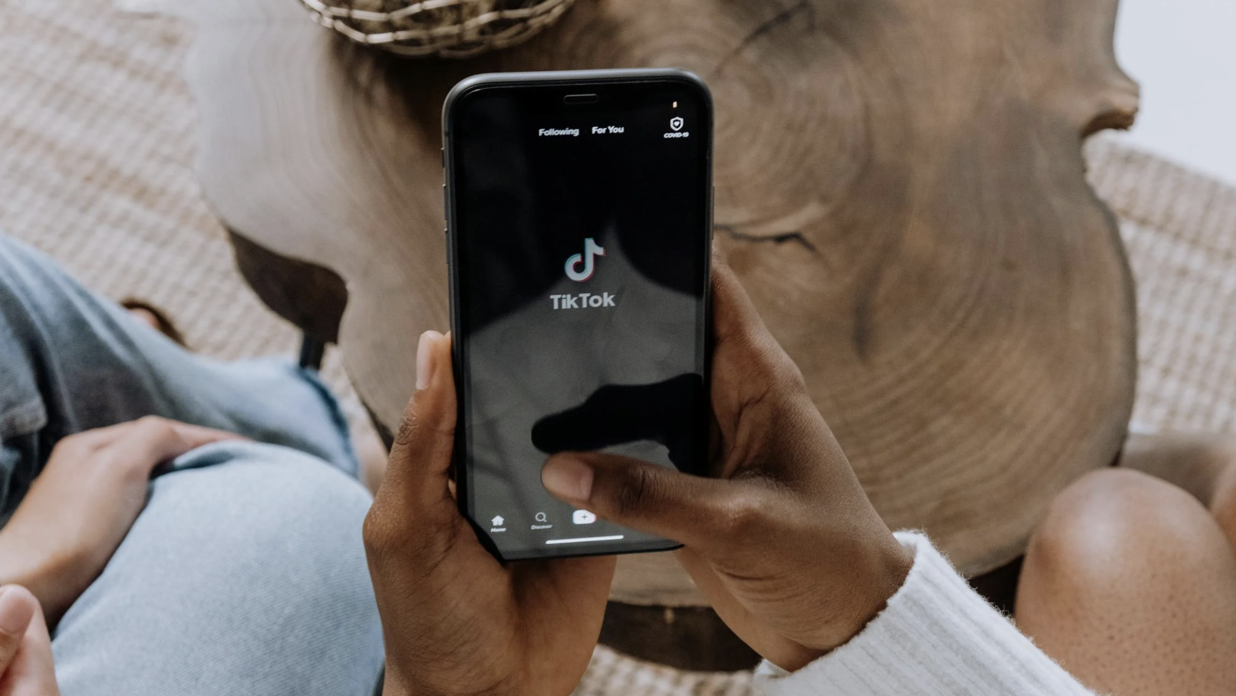 Man's hand holding phone with TikTok logo on screen.