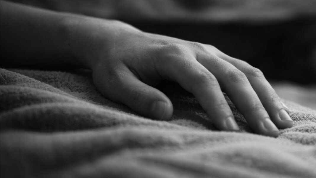 A symbolic image showing a lifeless hand resting on a bed, representing the tragic consequences of drug abuse.