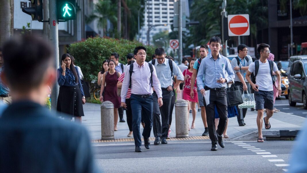 Office workers crossing the road at the end of their working day as they walk on the streets of the Central Business District (CBD)